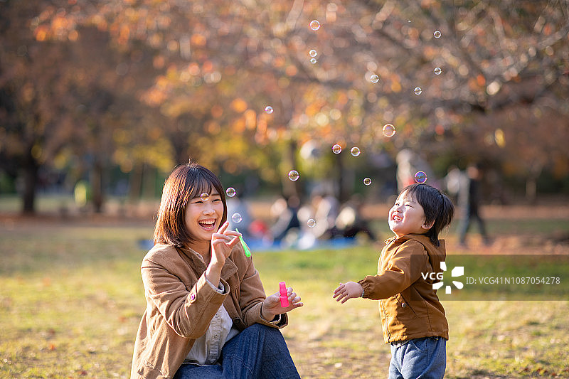 年轻的母亲和儿子在公园里玩肥皂泡图片素材