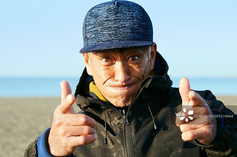 清晨，男人站在海滩上表情奇怪的肖像图片素材