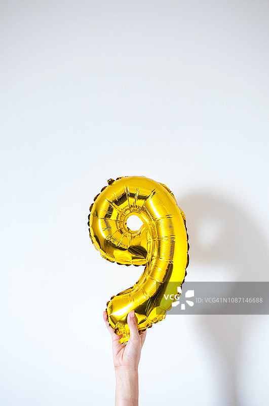 手持金色充气气球数字九图片素材