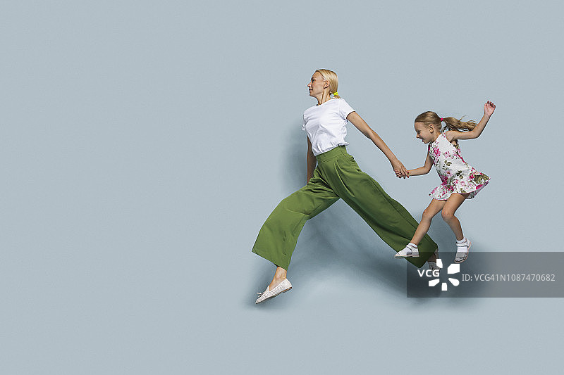 母女在蓝色背景下跳跃图片素材