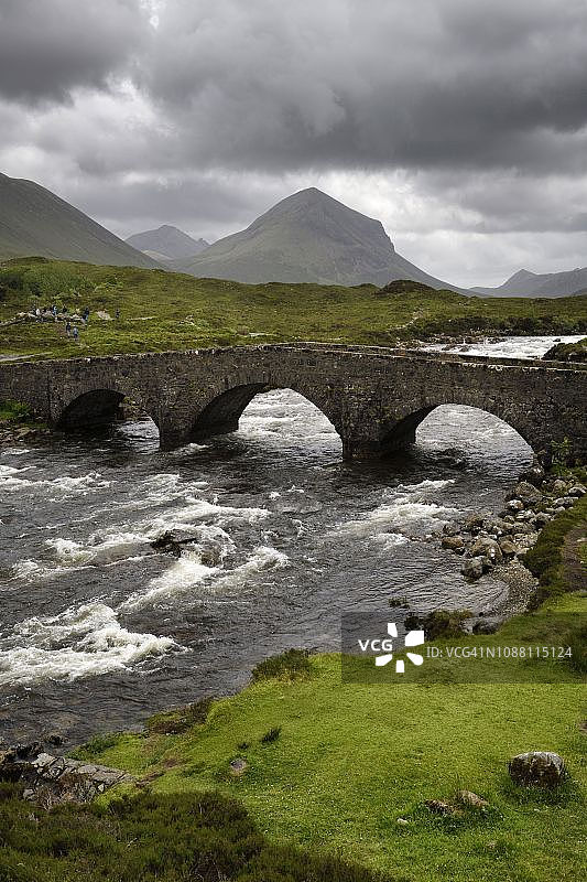 斯凯岛斯利加achan河上的斯利加achan老石桥，背景是红色丘陵山脉的马斯科峰，英国苏格兰图片素材