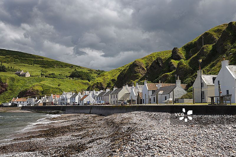 苏格兰阿伯丁郡彭南渔村的石头海滩和白色房屋，北海沿岸，绿色海崖图片素材