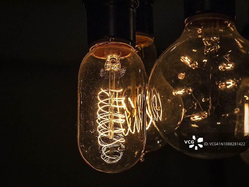 爱迪生灯泡在黑色背景下发光图片素材