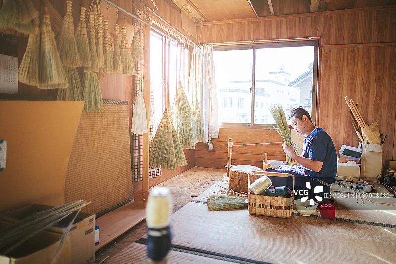 亚洲男人在他的工作场所制作扫帚。图片素材