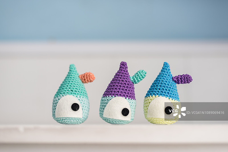 白色桌子上三个手工钩编的娃娃屋图片素材