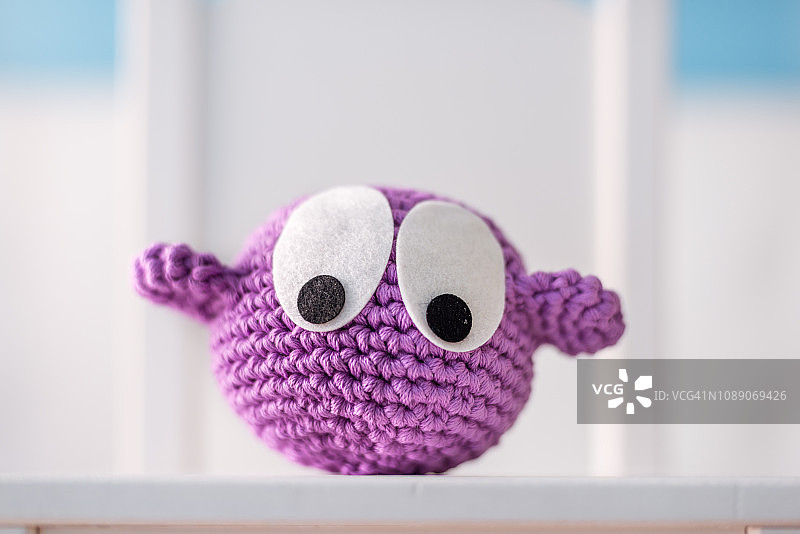 白色椅子上的手工钩针紫色小鸟图片素材