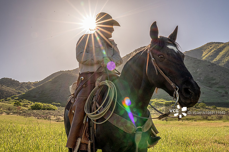 阳光下山中骑马的老牛仔图片素材