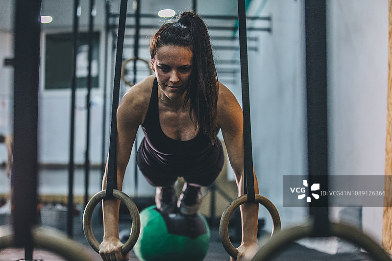 在吊环上锻炼的强壮女运动员图片素材