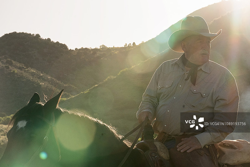 阳光下山中骑马的老牛仔图片素材