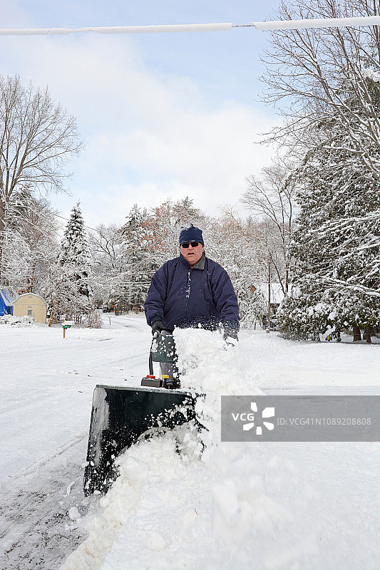 在冬天使用抛雪机除雪的中年男人图片素材