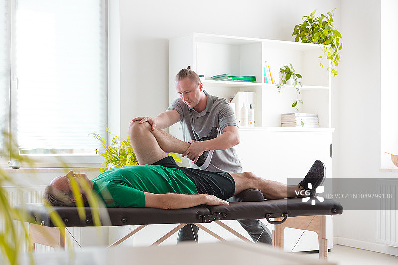 理疗师为老年男性伸展髋部图片素材