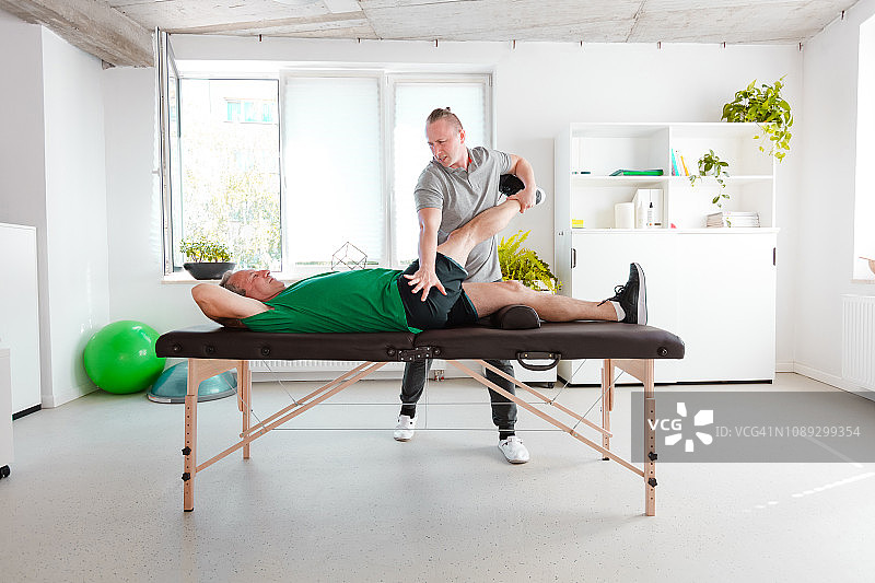 理疗师为老年男性伸展髋部图片素材