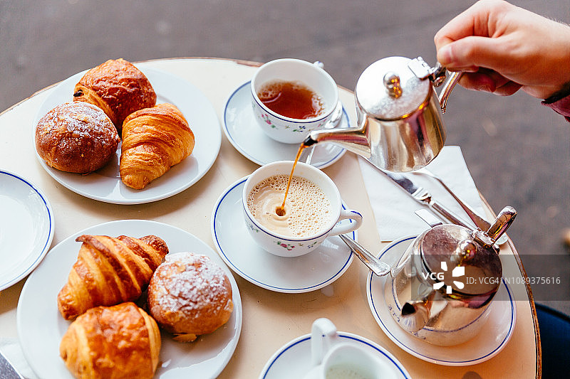 在路边咖啡馆吃早餐时倒茶图片素材