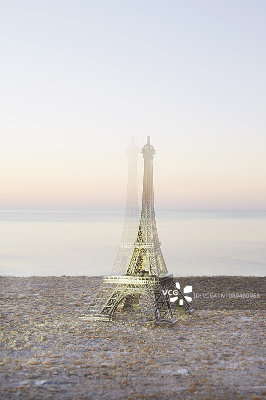 埃菲尔铁塔模型（纪念品）特写，以大海和日落为背景图片素材