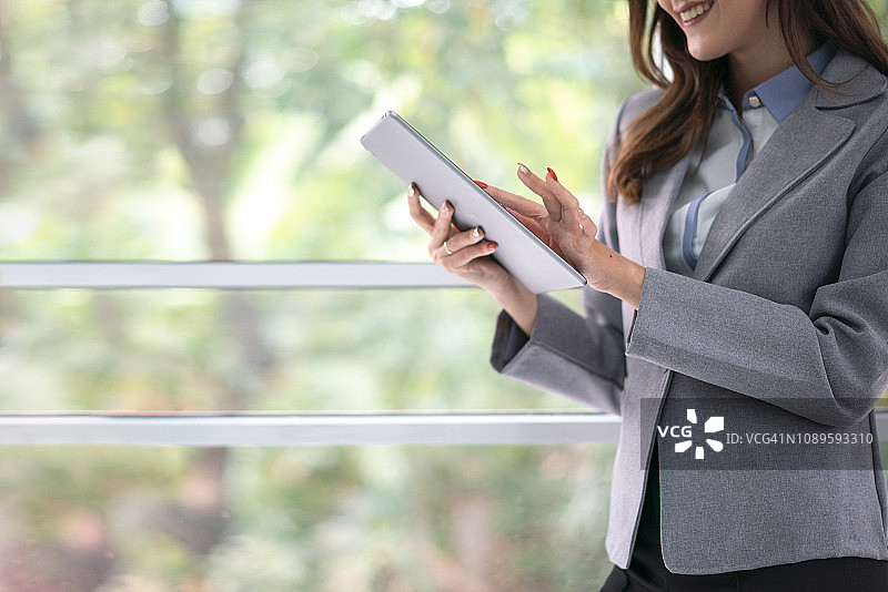 在办公室使用平板电脑阅读屏幕信息的红发女商人图片素材
