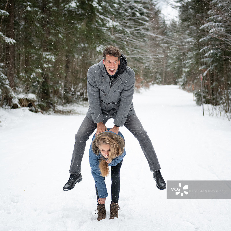 情侣在雪地里玩跳山羊，冬季恋情图片素材
