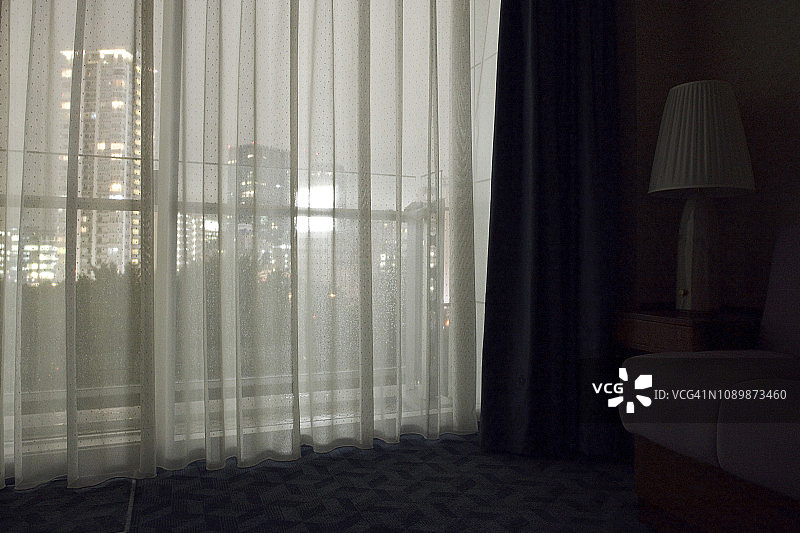 夜晚酒店房间的昏暗室内，配有薄纱窗帘图片素材
