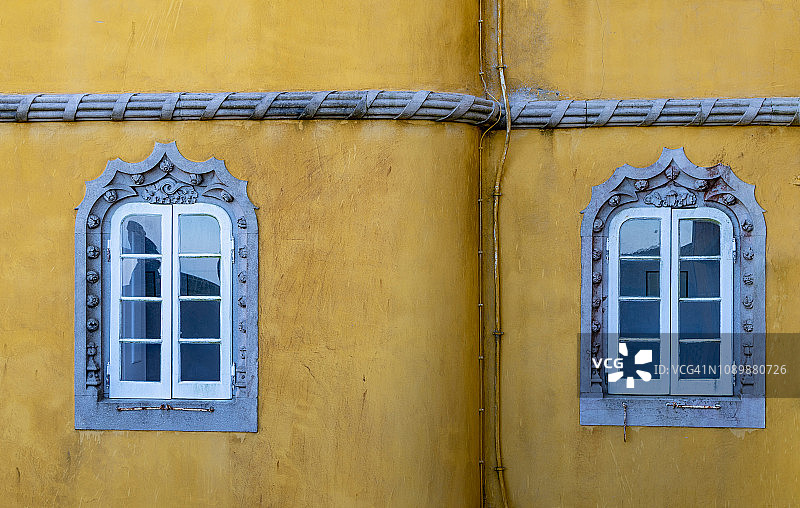 深黄色外墙上带有庄严装饰的两扇窗户图片素材