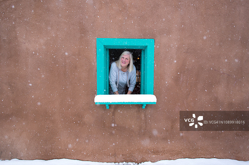 新墨西哥州圣菲：老土坯房窗边的雪景女人图片素材