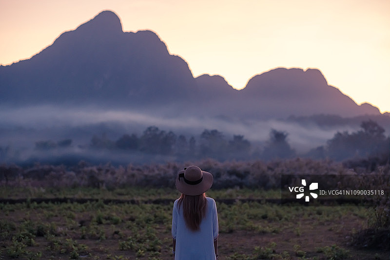 老挝日落时分，女子欣赏山景的背影图片素材