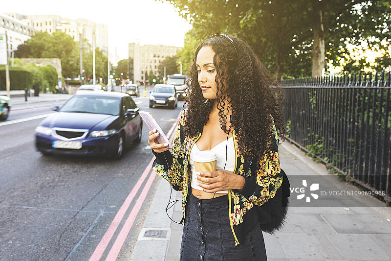 英国伦敦：在城市人行道上使用手机的年轻女子图片素材