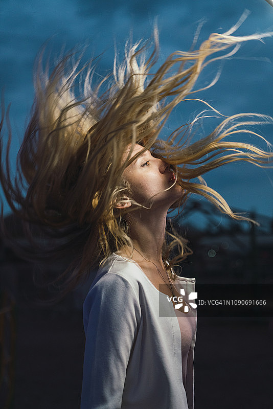 在户外夜晚甩头发的长发年轻女子图片素材