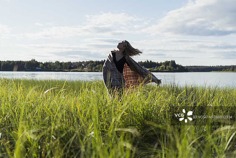 芬兰拉普兰湖边裹着毯子的女人图片素材