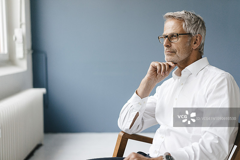 经理坐在办公室的椅子上，望着窗外思考图片素材