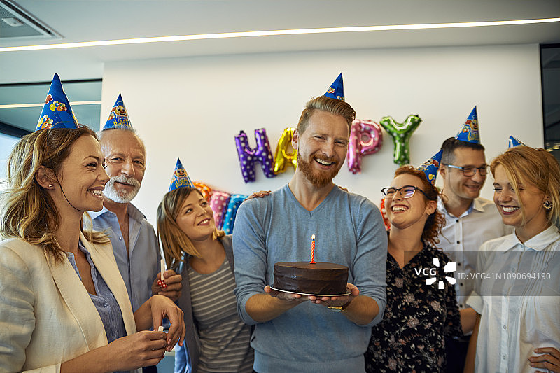 同事们在办公室举办生日庆祝活动，有蛋糕和派对帽图片素材