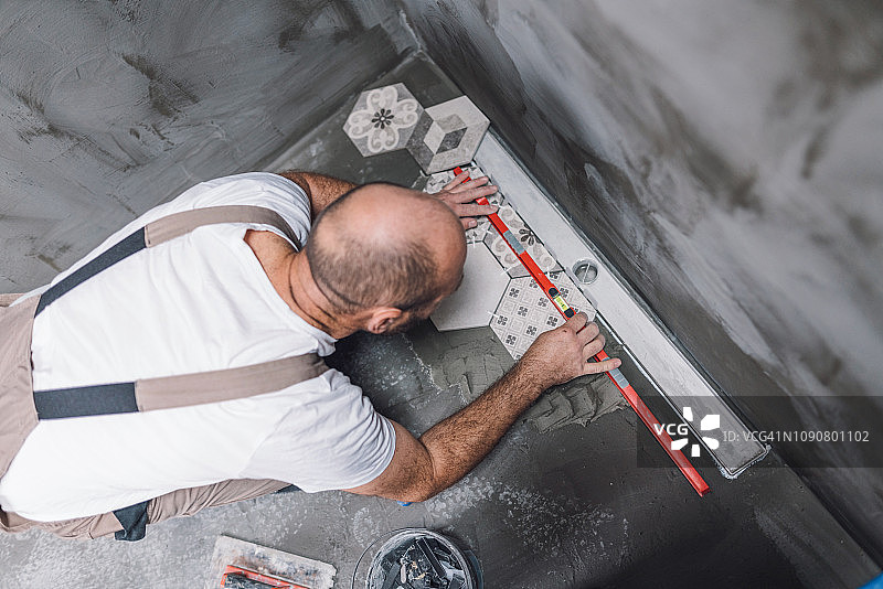 建筑工人在浴室地板上找平瓷砖图片素材