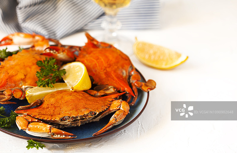 黑盘上的煮熟的螃蟹和一杯白葡萄酒图片素材