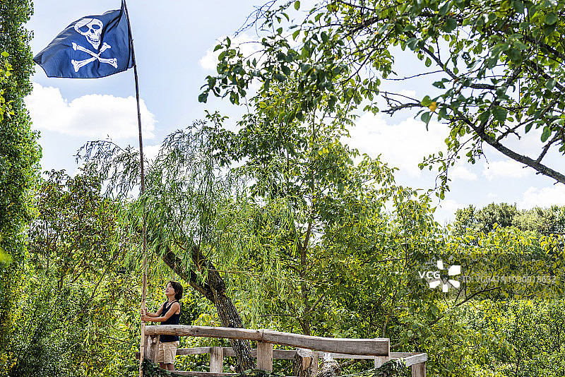 在带有海盗旗的树屋上的男孩图片素材