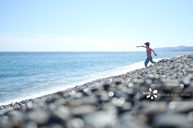 在海滩上扔石头的男孩图片素材