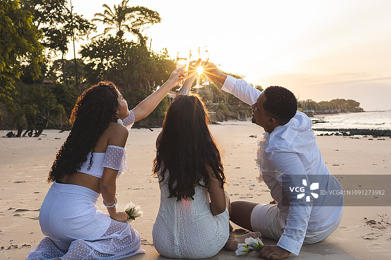 快乐的朋友在海滩上庆祝新年，举杯葡萄酒庆祝图片素材