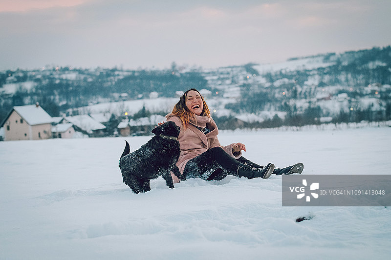 女人和狗在雪地里玩耍图片素材