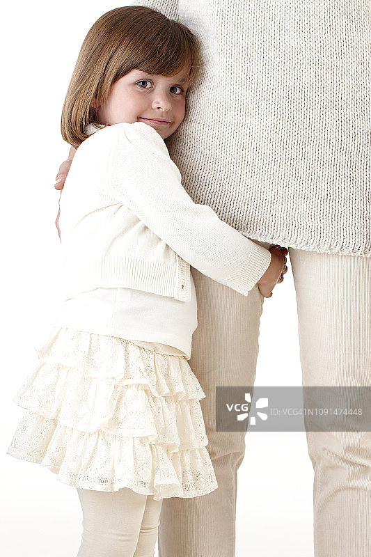 微笑的女孩抱着妈妈的腿图片素材