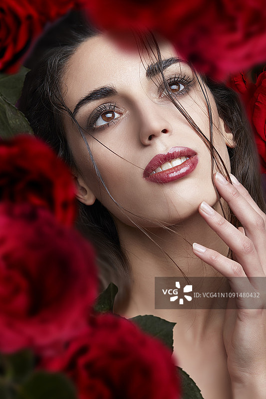 被鲜花环绕的涂着红色口红的美丽棕发女孩图片素材