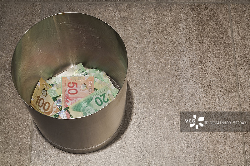 不锈钢垃圾桶里的加拿大20、50和100加元纸币图片素材