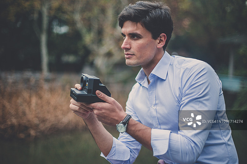 英俊的商人使用宝丽来相机图片素材