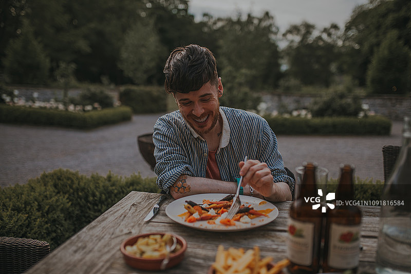 阳光明媚的日子里在户外用餐的年轻男子图片素材