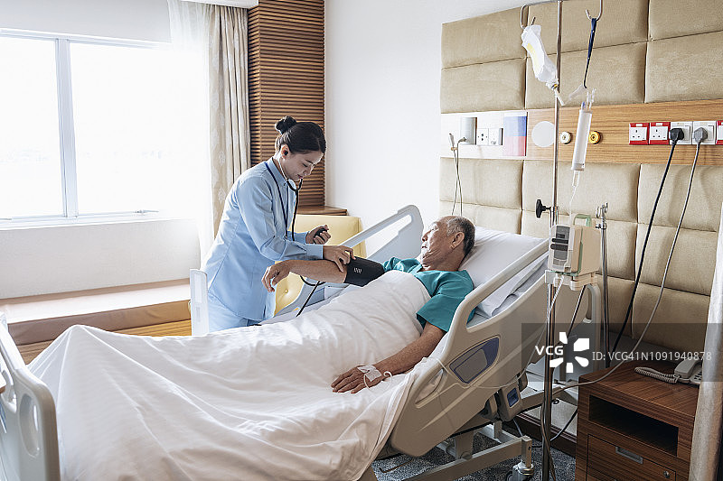 护士在病床上为老年男性测量血压图片素材