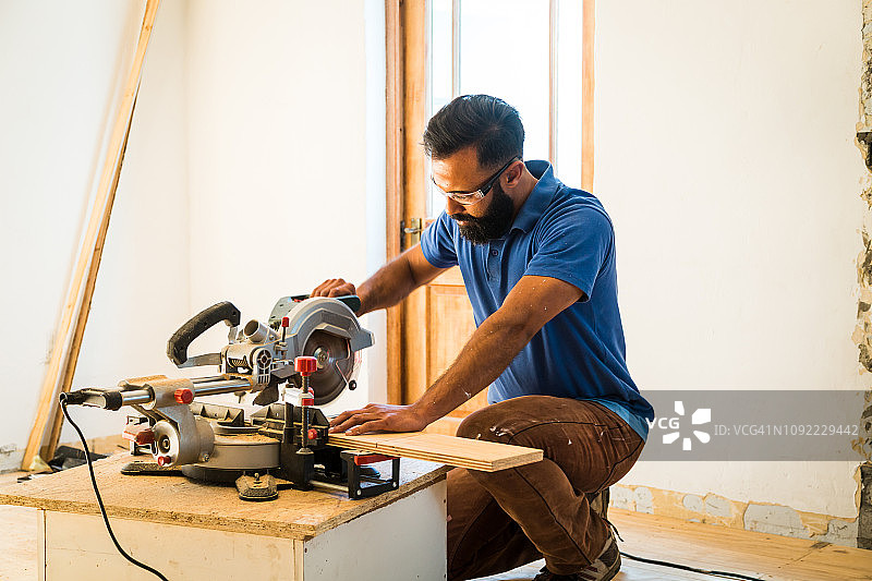 用电动锯切割木头的混血男子图片素材
