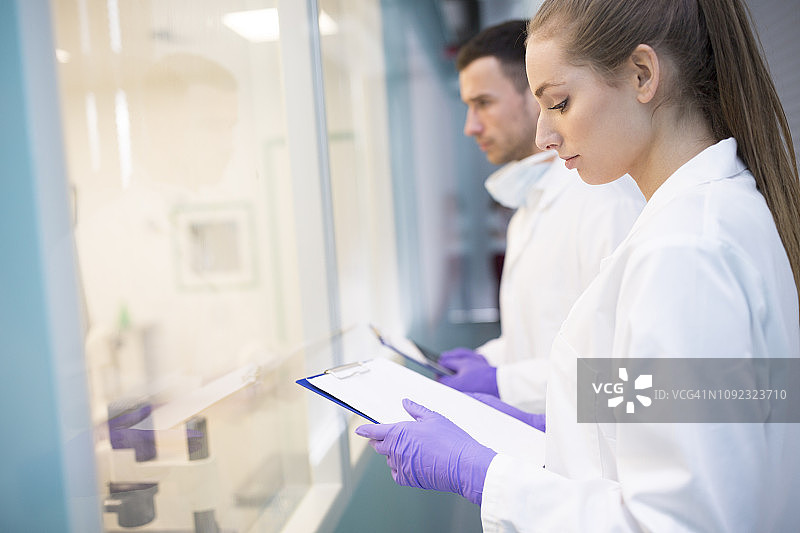 穿着实验服，拿着剪贴板的男人和女人图片素材