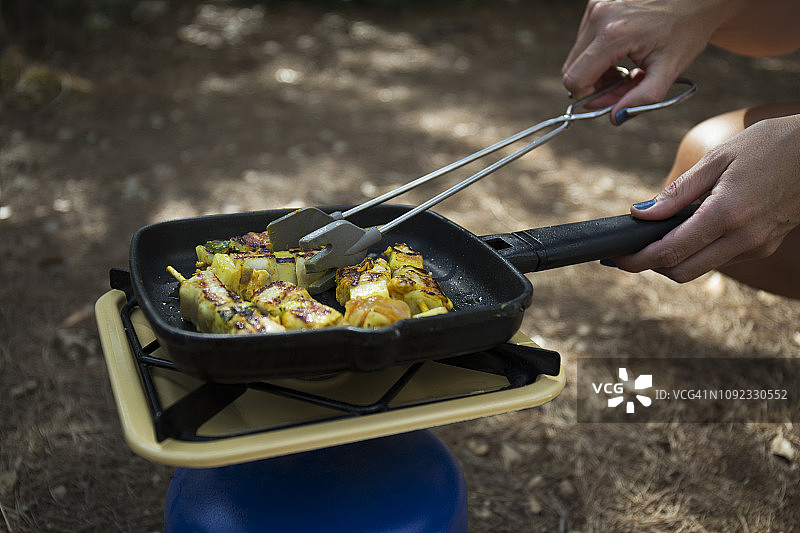 女人在煤气炉上烤蔬菜串，特写图片素材