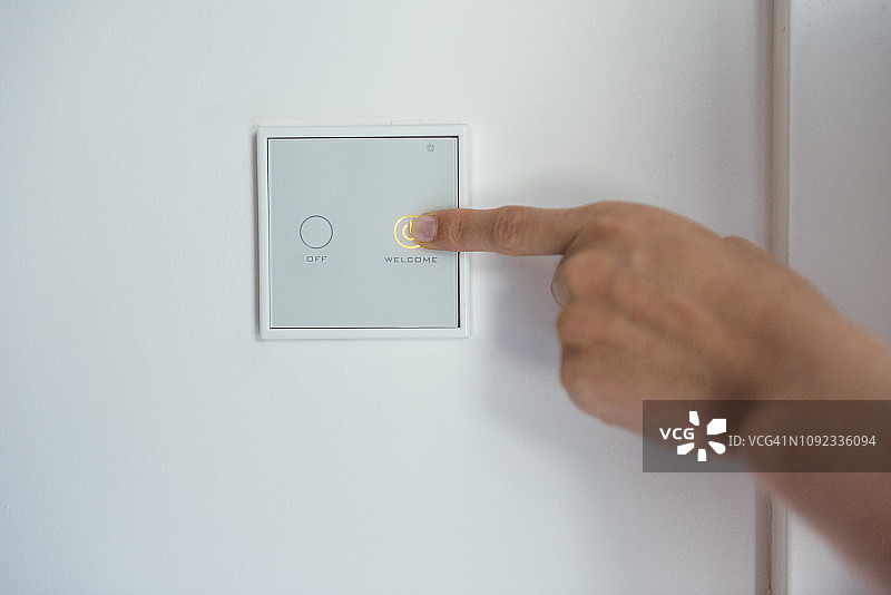 女人使用墙上的智能家居开关图片素材