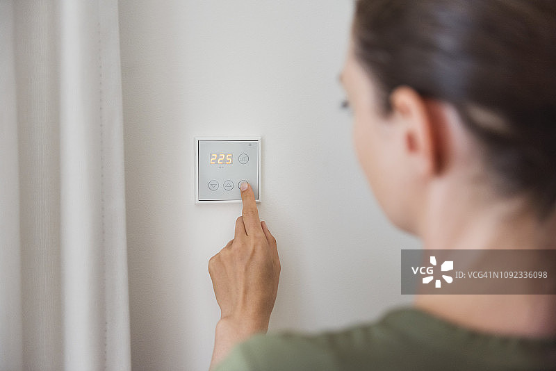 女人使用墙上的智能家居开关图片素材