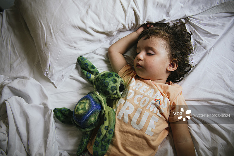 女宝宝睡在床上，T恤上写着“梦想成真”图片素材