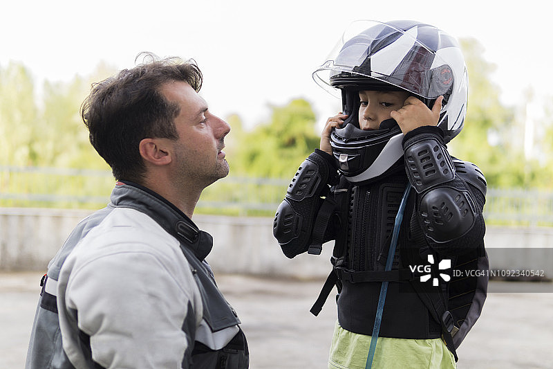 父亲看着儿子戴上摩托车头盔图片素材