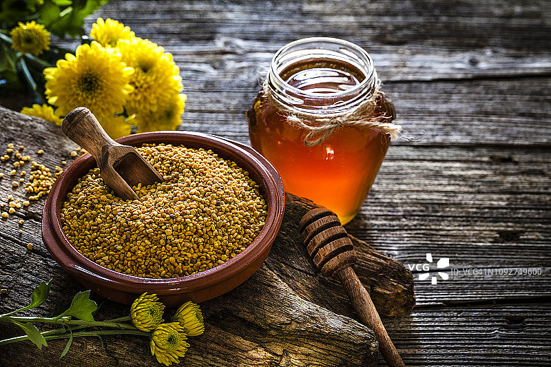 乡村木桌上的蜂花粉和蜂蜜罐图片素材
