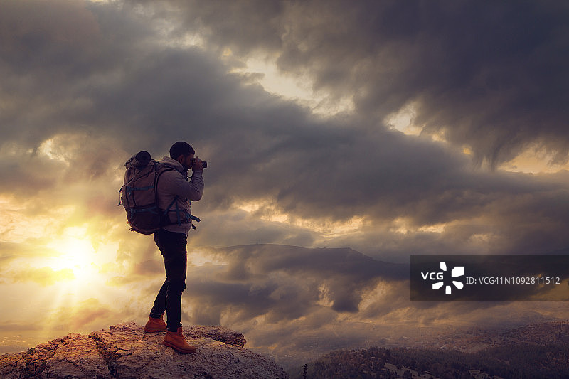 在山中拍摄日落的年轻游客图片素材